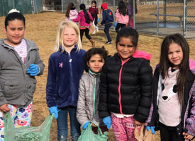  students holding plastic bags with garbage found on playground